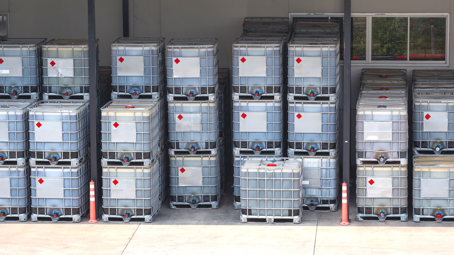 Bulk IBC chemical containers staged in front of a distribution warehouse